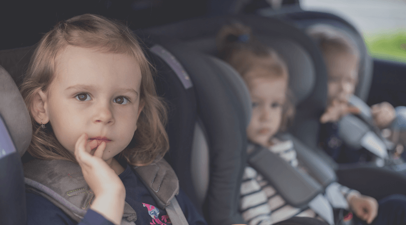 Three small sisters in car seats